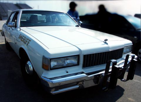 1998 Ford Crown Victoria - This 1980s sheriff car features a prominent push bumper and 'SHERIFF' lettering on the front fender.