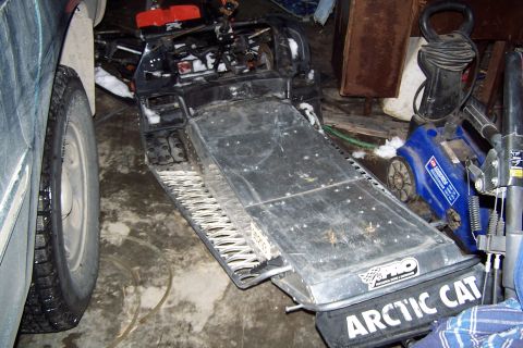 2004 Arctic Cat F-7 Firecat - A snowmobile with Arctic Cat branding is parked next to a car tire and other equipment.