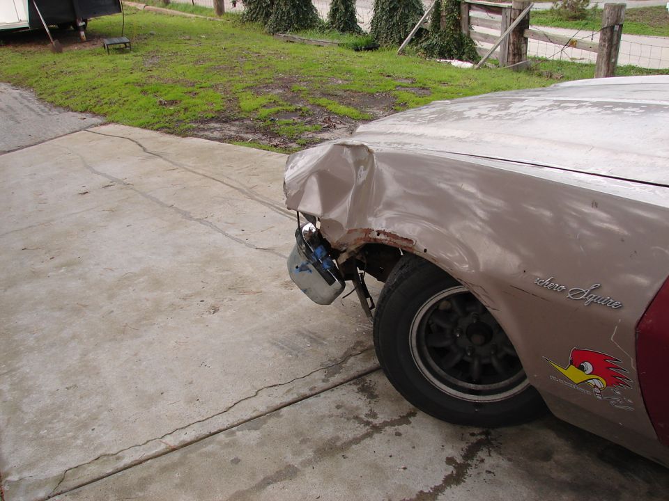 Tan Ford Ranchero Squire with crumpled front fender and exposed headlight, Woody Woodpecker decal
