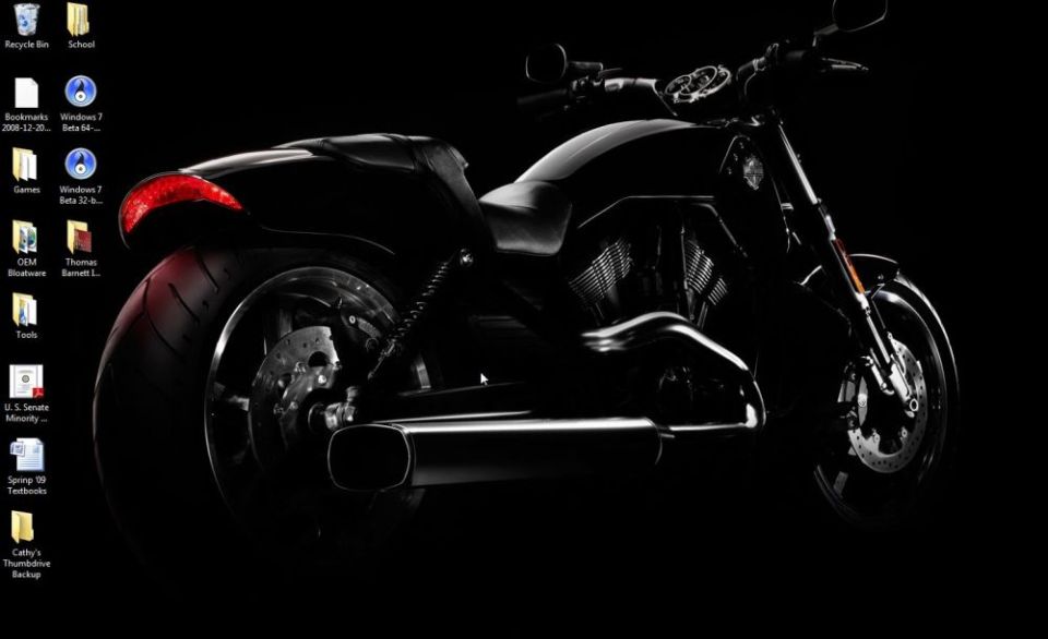 Black motorcycle side view, focusing on rear wheel and exhaust.