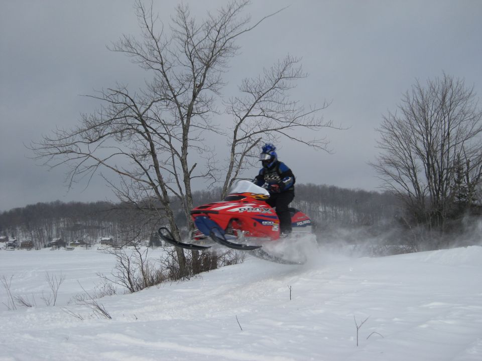Red and blue Polaris snowmobile jumping in the snow with rider.