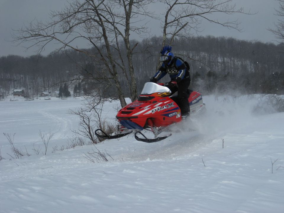 Person on a red Polaris snowmobile jumping in the snow.