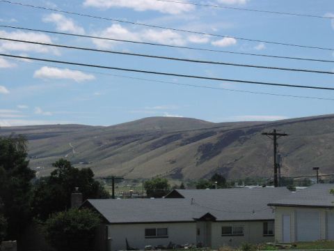 1981 Ford Bronco - A wide shot captures houses in a valley with rolling hills in the background under a partly cloudy sky.