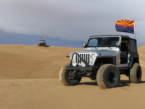 2004 Jeep Wrangler - A silver Jeep Wrangler Rubicon with an Arizona flag flies on a pole in a sandy desert landscape. Another Jeep is visible in the distance on…