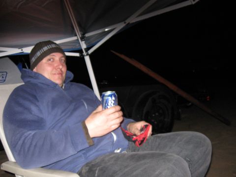 2004 Jeep Wrangler - A man sits in a chair holding a can of beer and a red bandana. He is wearing a blue hooded sweatshirt and a beanie, and is sitting under a…