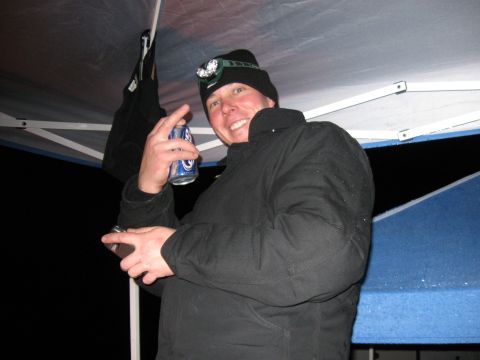 2004 Jeep Wrangler - A person wearing a black beanie with a headlamp is holding a can of beer and a cell phone under a canopy.
