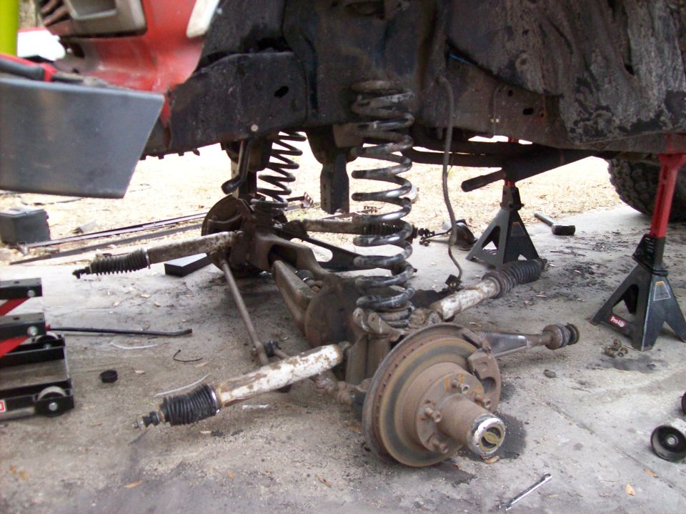 Disassembled front suspension and axle of a vehicle on the ground.