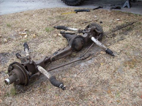 1986 Ford Bronco - A disassembled front axle assembly from a 1986 Ford Bronco is laid out on dry grass. The assembly includes the differential, steering compo…