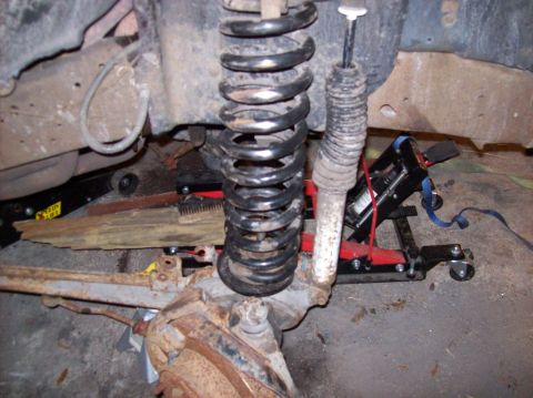 1986 Ford Bronco - The image shows the suspension system of a vehicle, likely an older SUV or truck, with a large coil spring and shock absorber prominently f…