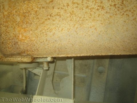 1987 Suzuki Samurai - Photo beneath a vehicle showing a rusty tank, frame rail and a small bracket fastener.