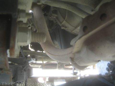 1987 Suzuki Samurai - Photo from beneath a vehicle showing an exhaust crossover pipe against the frame and floor.