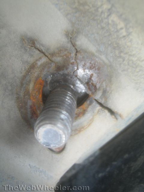 1987 Suzuki Samurai - Macro photo of a corroded threaded stud set in a cracked metal mounting surface.
