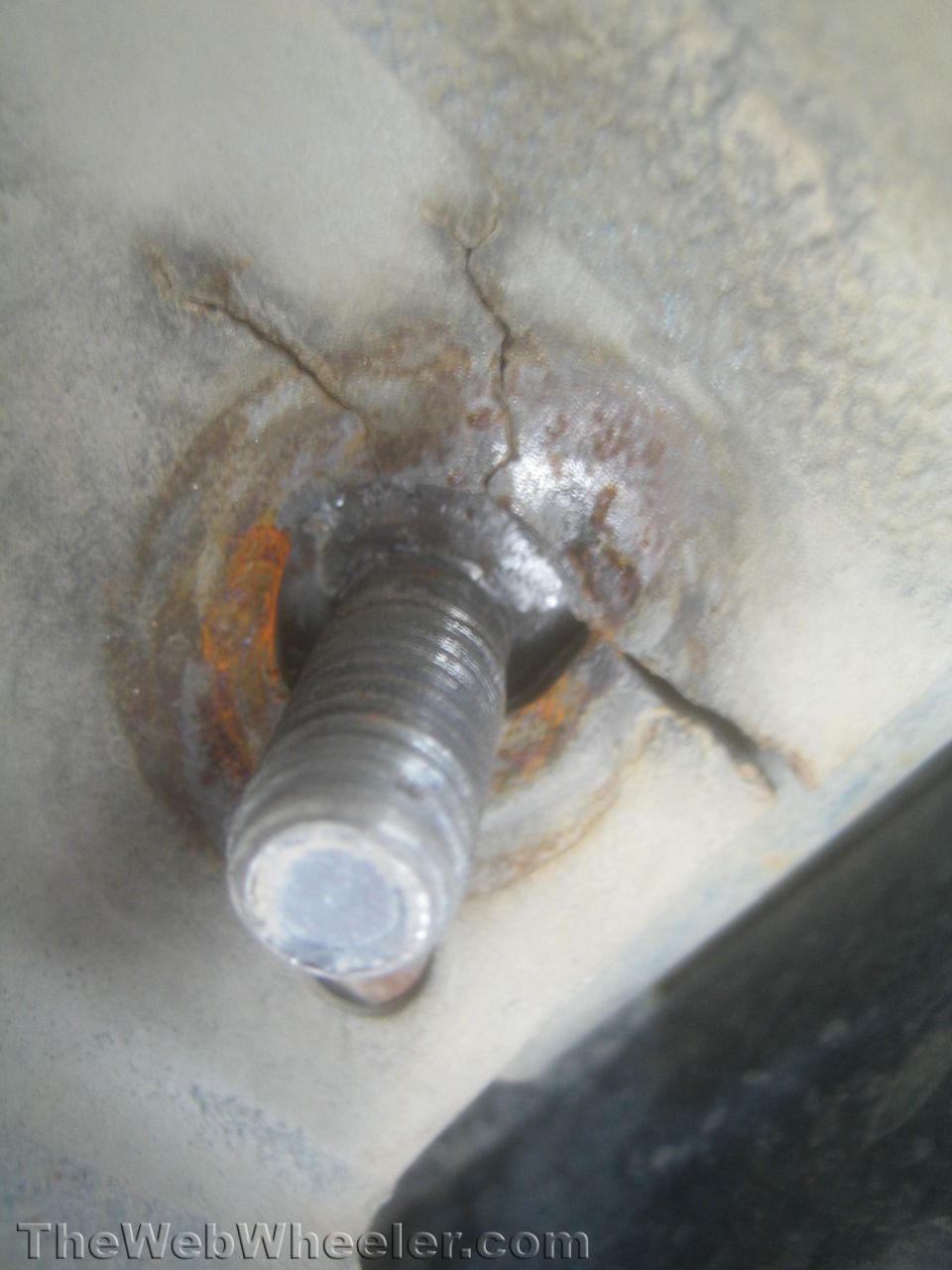 Close-up of a rusty cracked threaded stud in a metal mount