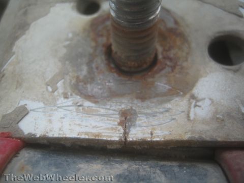 1987 Suzuki Samurai - Macro photo of a threaded stud passing through a rusty, cracked metal plate or bracket.
