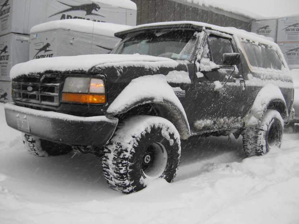 1995 Ford Bronco covered in snow, parked in a snowy environment.