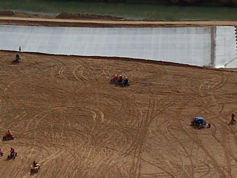 2004 Jeep Wrangler - Several ATVs and dune buggies are seen riding on a dirt track next to a large body of water covered with a white tarp.