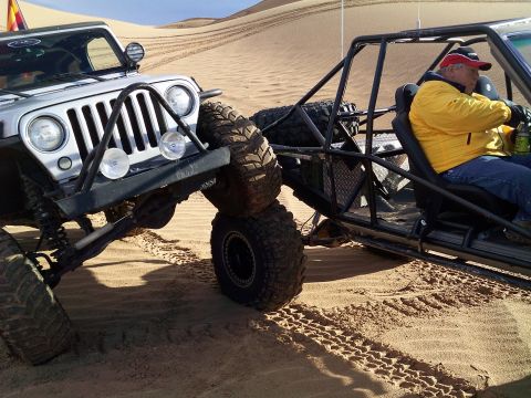 2004 Jeep Wrangler - Two off-road vehicles are positioned closely together on sand dunes. The vehicle on the left is a silver Jeep Wrangler, while the vehicle o…