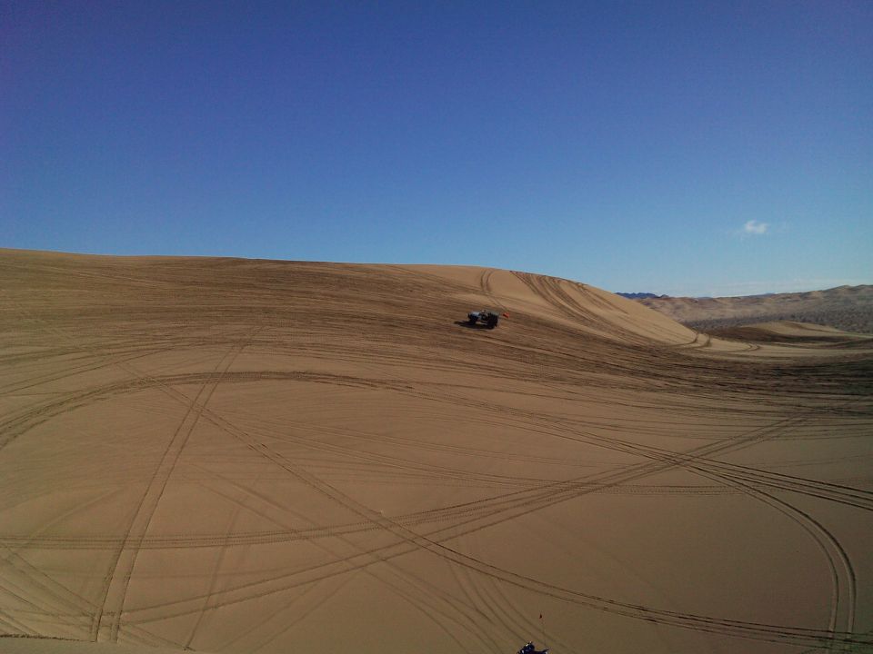 Jeep Wrangler on a sand dune with tire tracks.