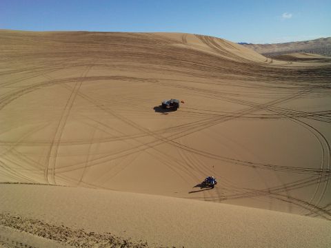 2004 Jeep Wrangler - Two off-road vehicles, a blue ATV and a dark-colored Jeep, are parked on a vast sand dune under a clear blue sky. Tire tracks crisscross th…