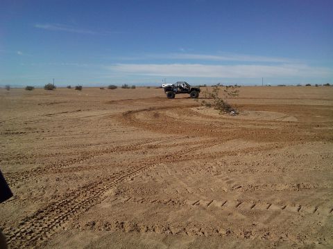 2004 Jeep Wrangler - A black off-road buggy with a roll cage is seen in a desert landscape, performing donuts on a sandy track. The vehicle is kicking up dust a…