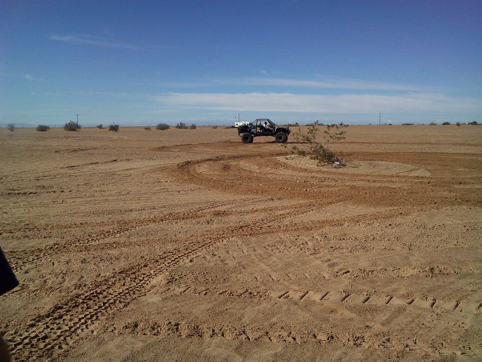 Black off-road buggy doing donuts in a desert.