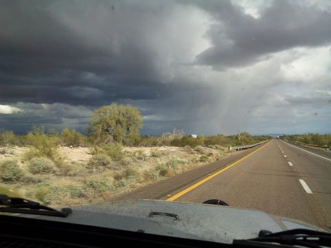 2004 Jeep Wrangler - View from a 2004 Jeep Wrangler on a highway under stormy skies, with a rainbow visible in the distance.