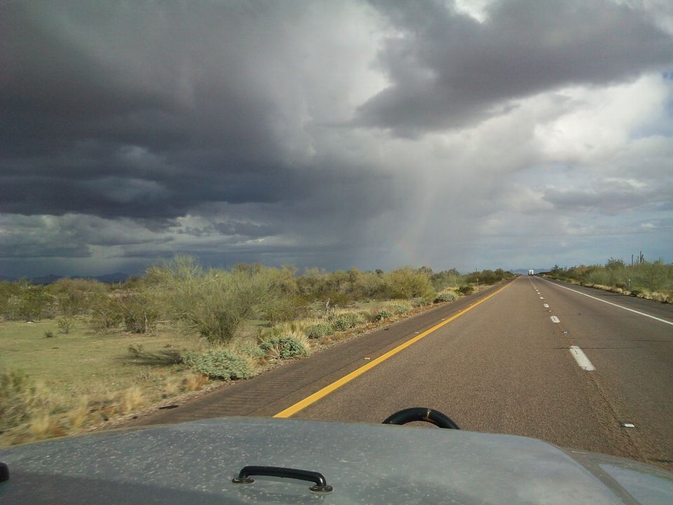 Desert road with storm clouds overhead, view from inside a vehicle