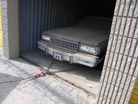 1991 Ford LTD Crown Victoria - Car covered in dust, parked inside a garage with a chain attached to its front.