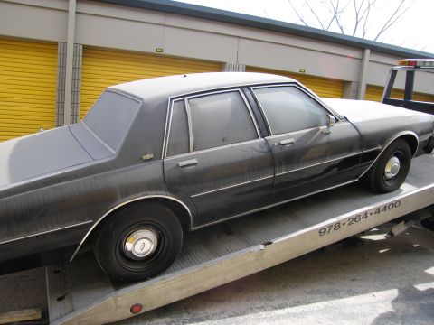 1991 Ford LTD Crown Victoria - This 1987 Chevrolet Caprice sedan is on a tow truck, with a phone number visible on the truck.