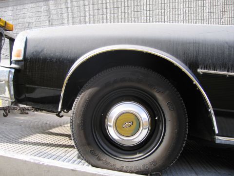 1991 Ford LTD Crown Victoria - Close-up of a black car's front fender and wheel, showing a Chevrolet emblem on the hubcap.
