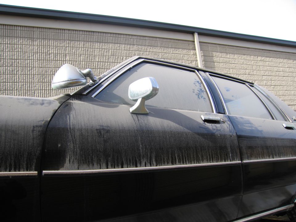 Close-up of a black sedan roofline, A-pillar and side mirror