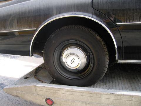 1991 Ford LTD Crown Victoria - Detail photograph of a Chevrolet wheel and hubcap on a flatbed, not a technical document.