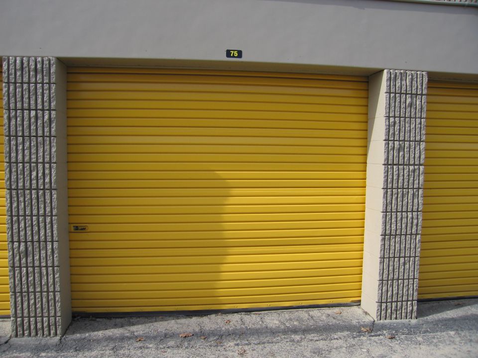 Two yellow roll-up storage unit doors with concrete pillars