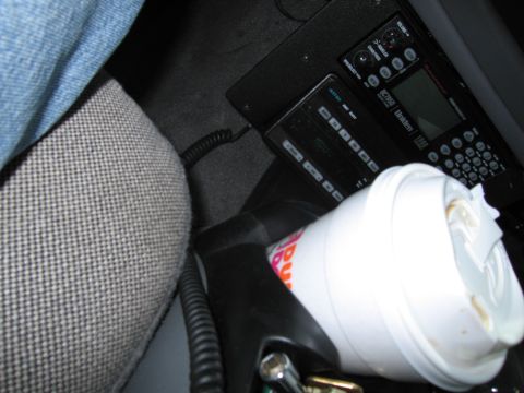1991 Ford LTD Crown Victoria - A close-up shot of a vehicle's interior reveals a coffee cup and radio equipment, with no clear year identification.