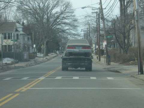 1991 Ford LTD Crown Victoria - A light-colored 1987 Chevrolet Caprice Classic is transported on a flatbed tow truck.
