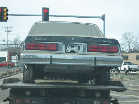 1991 Ford LTD Crown Victoria - A 1987 Chevrolet Caprice sedan is loaded onto a tow truck, seen from the rear.