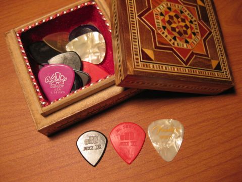 1989 Mazda MX-6 - A collection of guitar picks is displayed, some in a decorative wooden box and others laid out on a table.