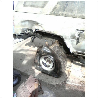 2004 Jeep Wrangler - The rear wheel well of a vehicle is severely damaged, with a flat tire visible.