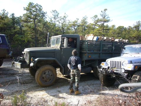 2004 Jeep Wrangler - A military truck and a Jeep Wrangler are parked off-road, with a person standing between them.
