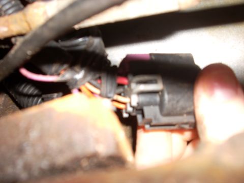 2000 Chevrolet Tahoe - A hand connects an electrical plug with multiple wires, obscuring the vehicle's identity.