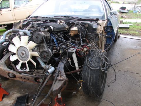 1973 Ford Ranchero - Front-end teardown of a project car in a gravel driveway, with the hood, grille, radiator support and front sheetmetal removed to expose th…