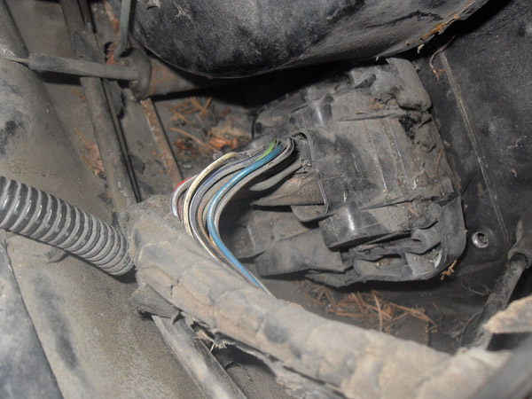 Bundle of colored wires routed near a dirty undercarriage component
