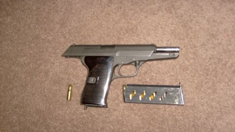 1995 Ford C-350 (Centurion Conversions) - A handgun, a single cartridge, and a loaded magazine are displayed on a brown carpet.