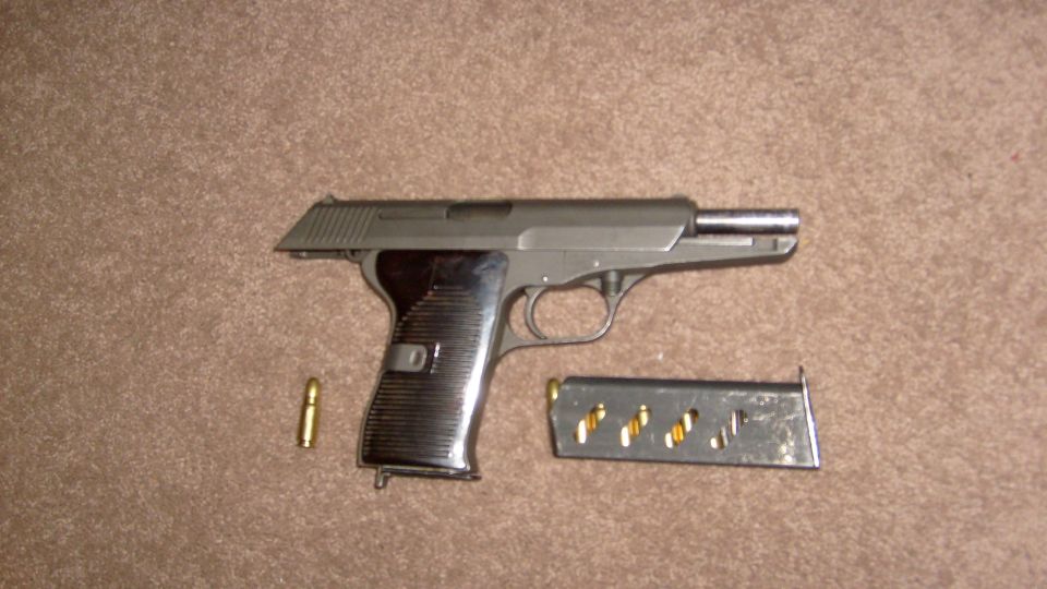 pistol with one round and a loaded magazine on a carpeted surface