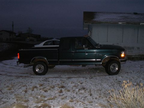 1997 Ford F-250 - Side view of a dark green 1997 Ford F-250 truck parked in a snowy area.