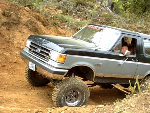 1995 Ford Bronco - This lifted 1995 Ford Bronco navigates a steep dirt trail, its off-road capabilities.