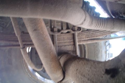 1979 Ford Bronco - The underside of a vehicle reveals its suspension and exhaust system components.
