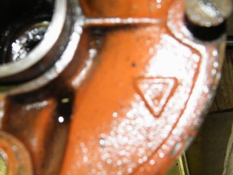 1912 Ford Model T - Close-up of an orange metal component, possibly from a vehicle's rear axle, a distinct triangular marking.