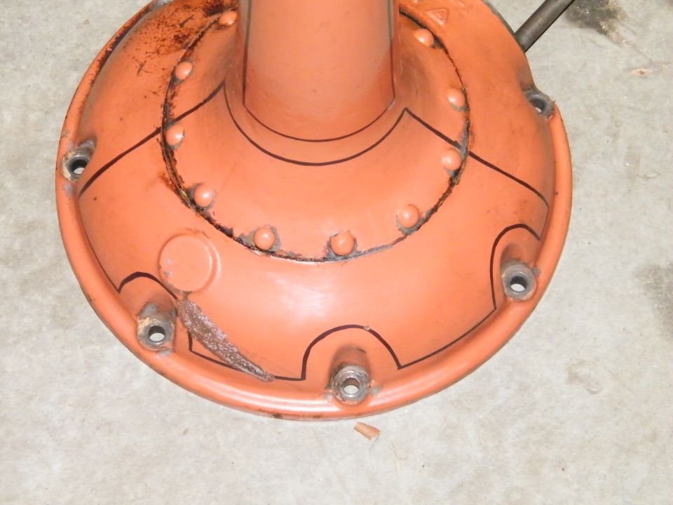 Freshly painted orange Model T rear axle and torque-tube housing standing on a garage floor