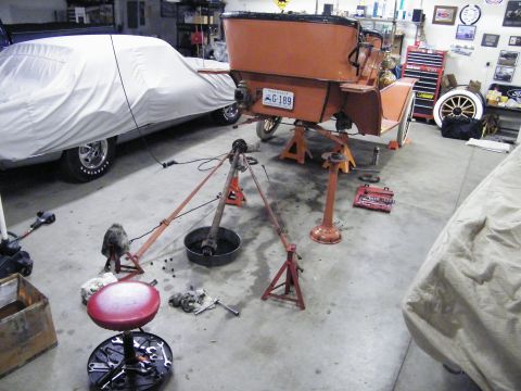 1912 Ford Model T - A vintage car is being worked on in a garage, with its rear axle disassembled and parts laid out.